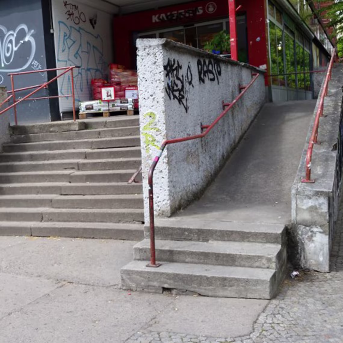 Schwer zugängliche Rampe mit Treppe, verfallener Einganz zu einem Supermarkt, der es beinträchtigen Personen nicht zulässt den Eingang zu betreten.
