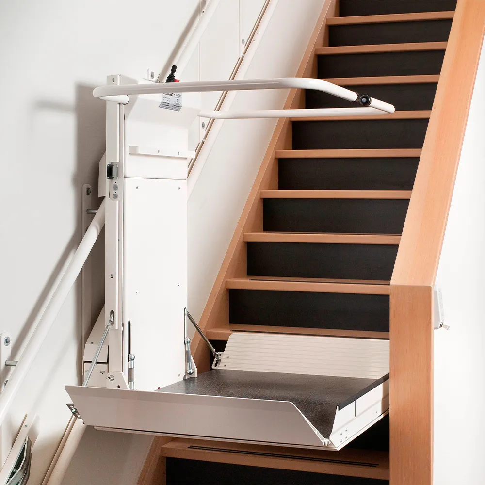 Plattformlift in weiß ist an einer Holztreppe angebracht.